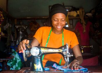 portrait of a young african female tailor smiling while working with her sewing machine