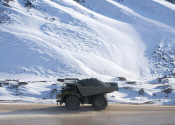 Dump truck loaded with ore driving through a snow covered open pit mine