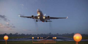 Airplane taking off from the airport runway at night. 3d rendering of a commercial flight taking off from an illuminated airstrip