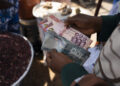 A customer counts Ghana cedi banknotes at the Nima market in Accra, Ghana on Monday, March 11, 2024